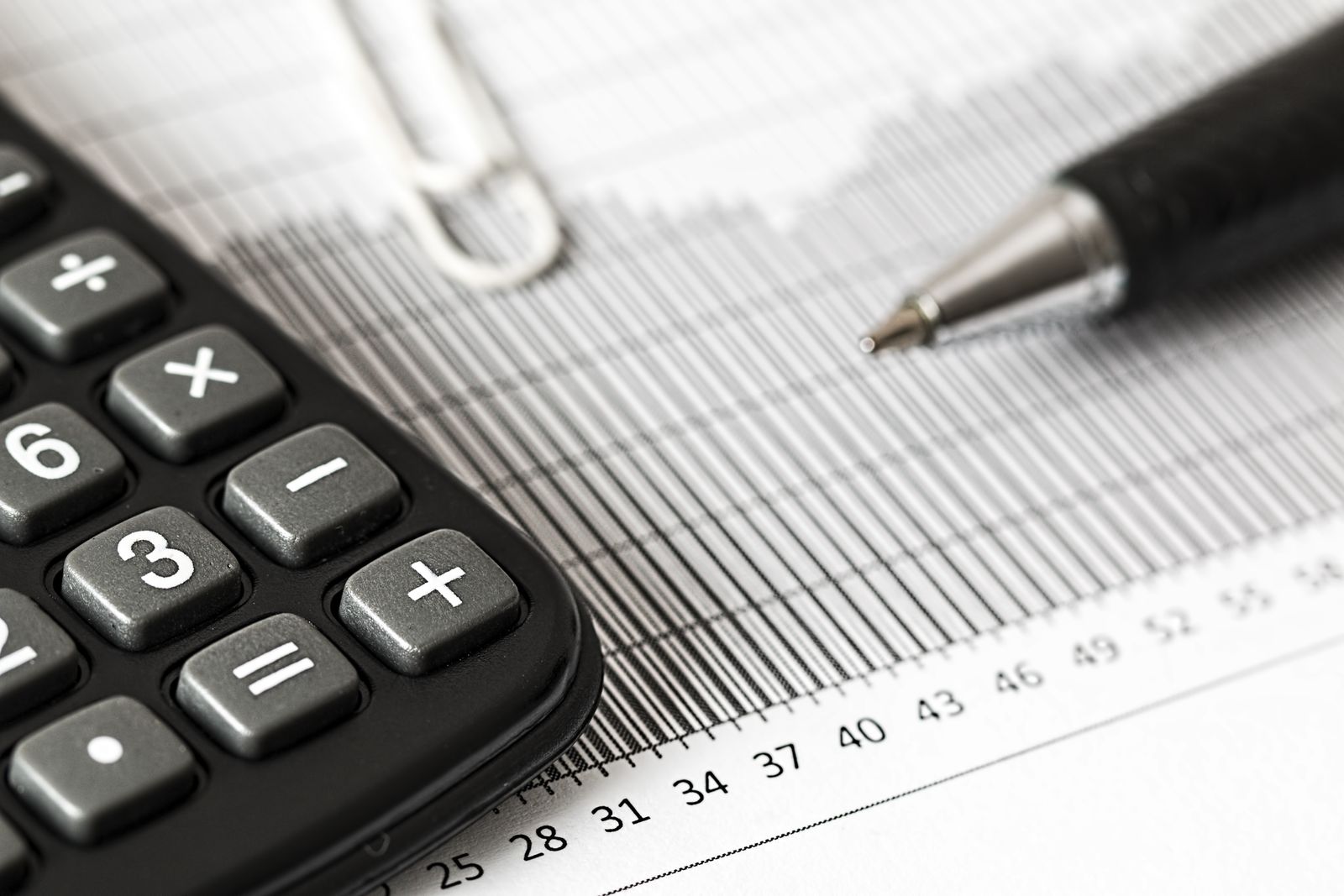 A calculator and a pen on a printed bar chart