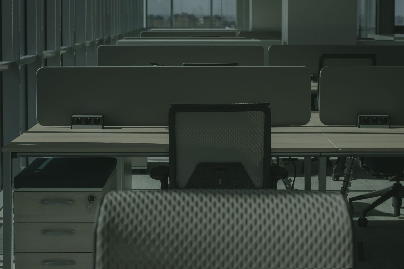 Rows of empty desks and office chairs in an open-plan office