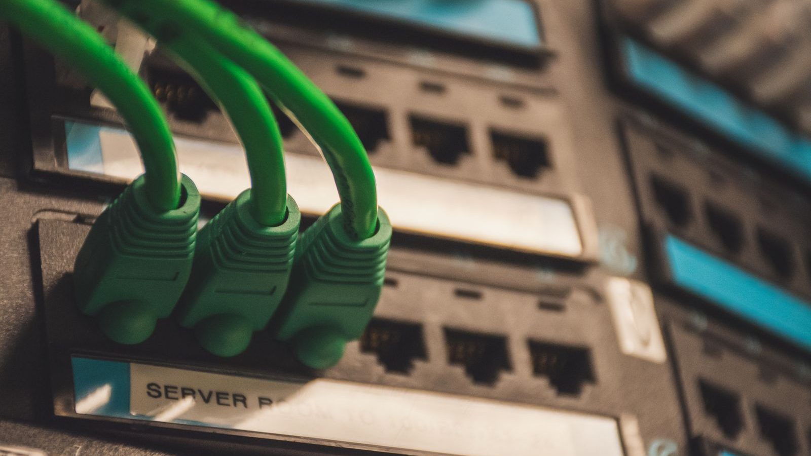 Three green network cables plugged into a server patch panel